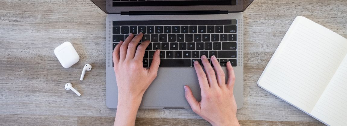 Hands typing on a laptop at a desk