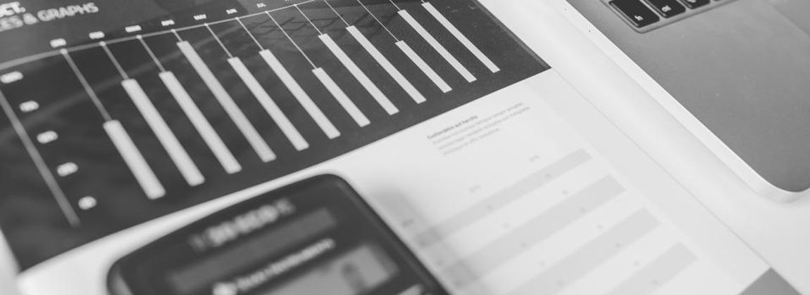 Printed bar charts beside a laptop