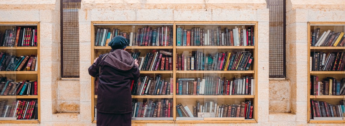 A person browsing books in glass-fronted outdoor bookcases