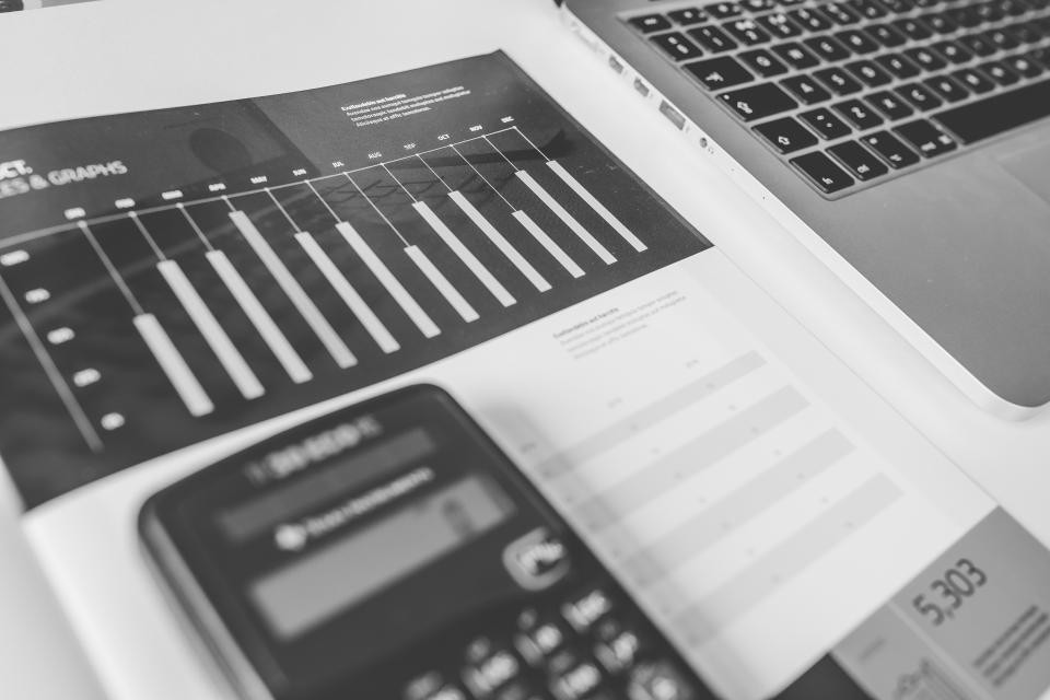 A printed bar chart, a data table and a calculator on a desk