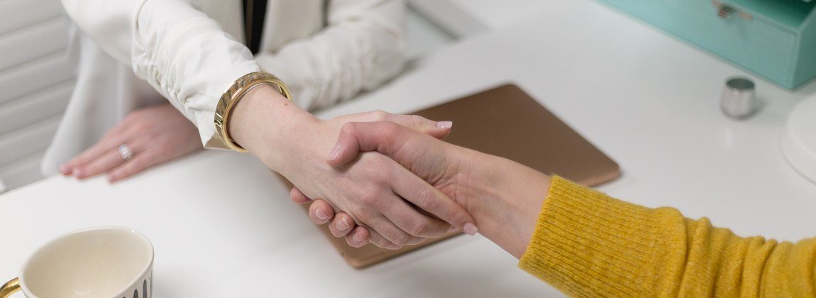 Two people shaking hands across an office desk