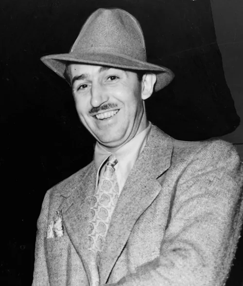 Walt Disney smiling in a fedora and tweed jacket, photographed in 1938