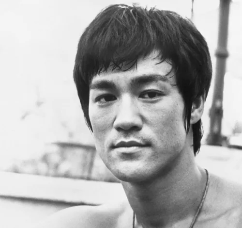 Bruce Lee looking at the camera with dark swept hair in a black-and-white publicity photograph from 1971
