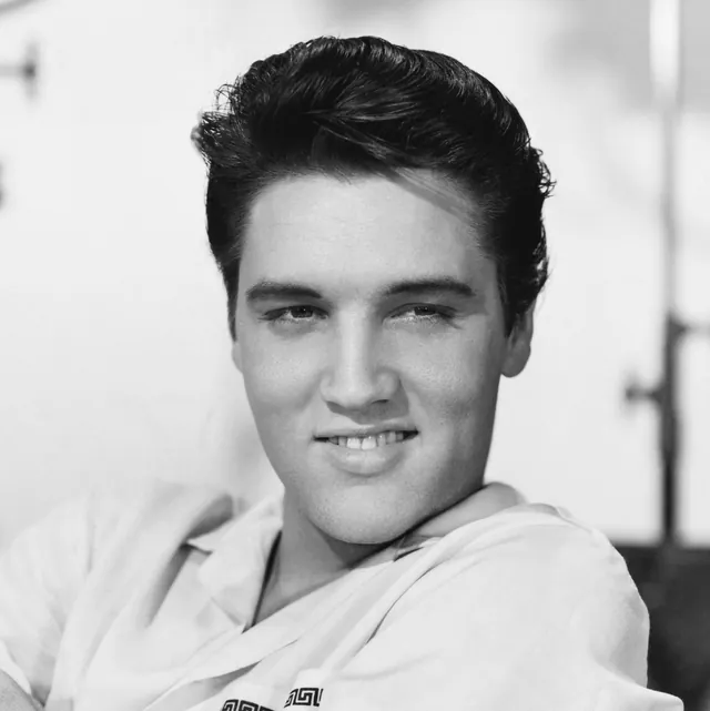 Elvis Presley smiling in a light open-collared shirt in a 1958 magazine photograph