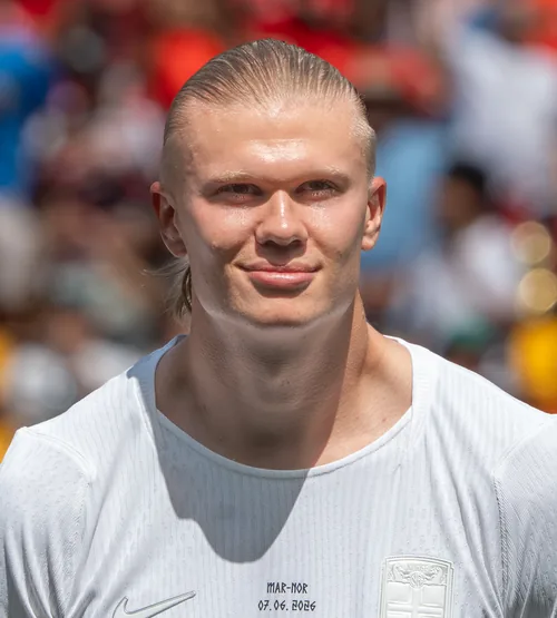 Erling Haaland with slicked-back hair smiling in a white number 9 shirt in June 2026