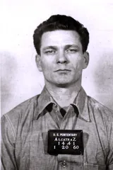 Frank Morris in a 1960 booking photograph from the U.S. Penitentiary at Alcatraz, wearing a work shirt and holding a placard that reads Alcatraz 1441