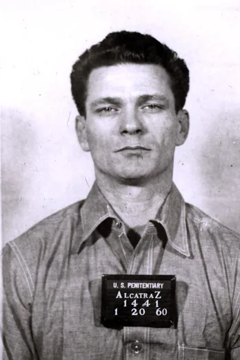 Frank Morris in a 1960 booking photograph from the U.S. Penitentiary at Alcatraz, wearing a work shirt and holding a placard that reads Alcatraz 1441
