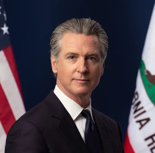 Gavin Newsom with swept-back gray hair in a dark suit, white shirt and dark tie, in his 2026 official portrait as Governor of California
