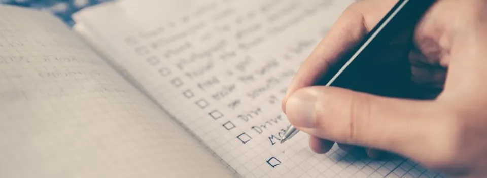 A hand ticking boxes on a checklist in a notebook