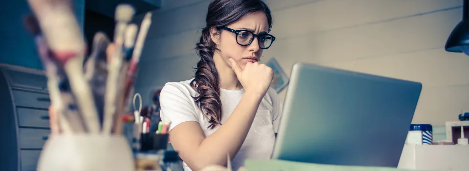 A woman at her desk thinking through a problem, with her laptop open