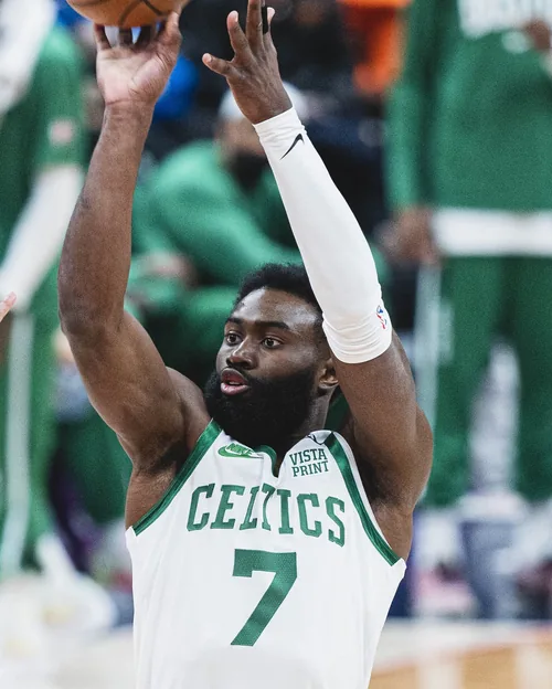 Jaylen Brown in a white Boston Celtics number 7 jersey with both arms raised during a game against the Washington Wizards on January 23, 2022