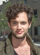 Penn Badgley, the actor who played Joe Goldberg in the series You, with tousled dark curly hair and light stubble, in an olive-green jacket over a dark shirt, photographed outdoors in September 2012