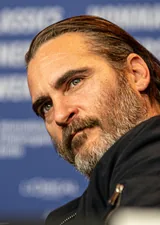 Joaquin Phoenix, the actor who played the Joker in the 2019 film Joker, in a black jacket with his head tilted, at the Berlin International Film Festival press conference in February 2018