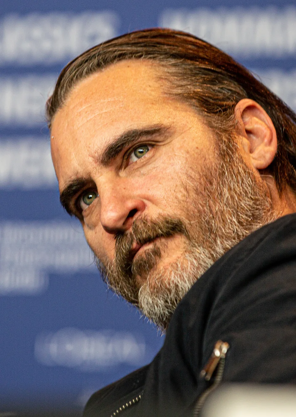 Joaquin Phoenix, the actor who played the Joker in the 2019 film Joker, in a black jacket with his head tilted, at the Berlin International Film Festival press conference in February 2018