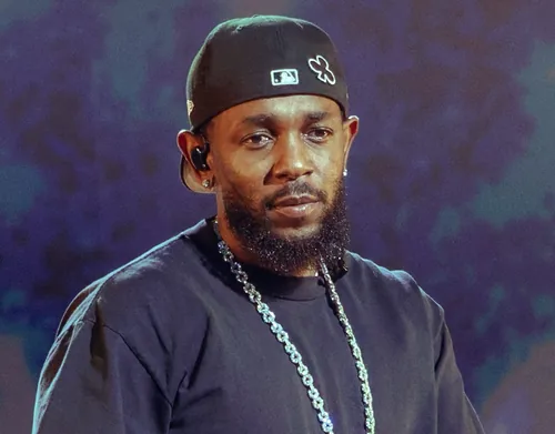 Kendrick Lamar in a black baseball cap and a dark T-shirt with a chain necklace, performing in July 2025