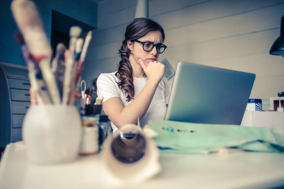 A woman at her desk thinking through a problem, with her laptop open