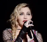 Madonna singing into a microphone in a black lace sleeve at the Rebel Heart Tour in Stockholm in November 2015