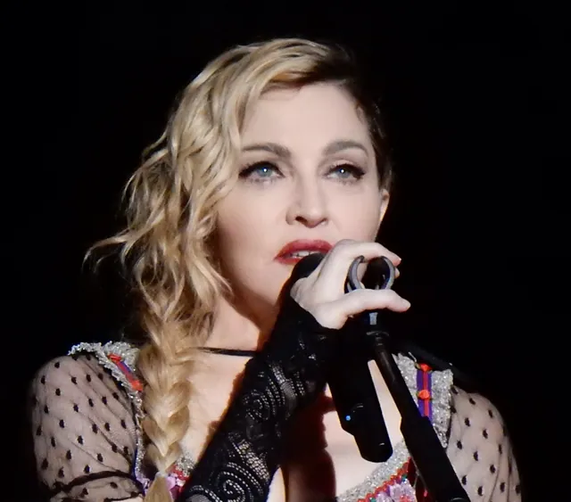 Madonna singing into a microphone in a black lace sleeve at the Rebel Heart Tour in Stockholm in November 2015