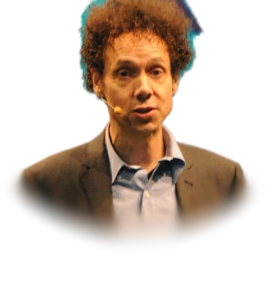 Malcolm Gladwell with curly reddish-brown hair in a brown jacket and a light-blue open-collared shirt, speaking on stage in November 2011