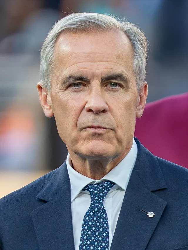 Mark Carney, Prime Minister of Canada, with short silver-grey hair, in a navy suit, white shirt and a blue patterned tie with a small lapel pin, photographed in July 2026