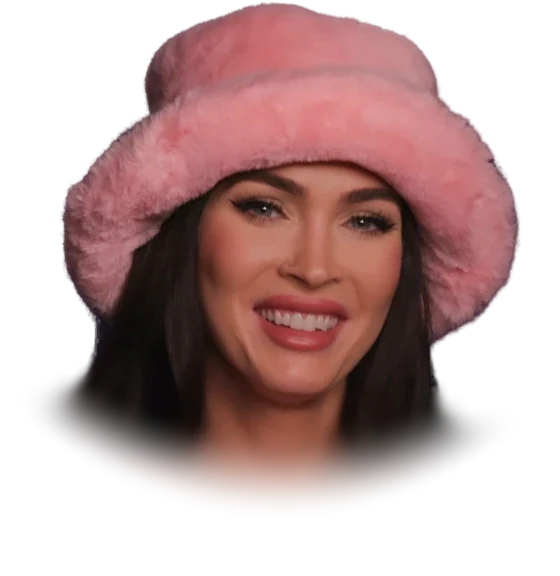Megan Fox smiling in a pink fur bucket hat and a pink cardigan in 2023