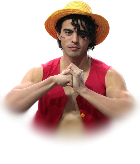 A cosplayer dressed as Monkey D. Luffy from One Piece, in a straw hat and an open red vest, with both hands pressed together in front of the chest, photographed at a convention in December 2015