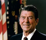 Ronald Reagan smiling in a dark suit, white shirt and maroon patterned tie, in his official presidential portrait from February 1981