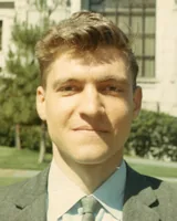 Ted Kaczynski as a young assistant professor of mathematics, smiling faintly in a gray jacket, light shirt and green tie, outdoors at the University of California, Berkeley, in June 1968