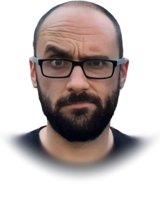 Michael Stevens, creator of the Vsauce channel, bald with a dark beard and black-framed glasses, in a black T-shirt, looking straight at the camera in July 2016